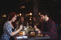 Счастливые друзья наслаждаются едой в баре — стоковое фото