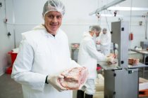 Portrait de boucher détenant de la viande à l'usine de viande — Photo de stock