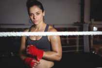 Retrato del boxeador femenino con correa roja en la muñeca en el gimnasio - foto de stock