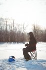 Pescador de gelo pescando em paisagens nevadas e árvores — Fotografia de Stock