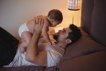 Father playing with baby boy in bedroom at home — Stock Photo