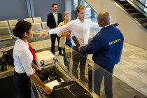Guardia di sicurezza che perquisisce i passeggeri con metal detector al terminal dell'aeroporto — Foto stock