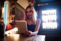 Улыбающаяся женщина с помощью цифровой тарелки в баре — стоковое фото
