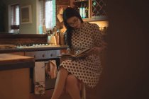 Frau liest zu Hause in der Küche ein Buch — Stockfoto
