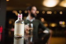 Gros plan de la petite bouteille de liqueur sur la table dans le bar — Photo de stock