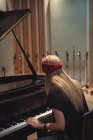 Vista posteriore di una donna che suona un pianoforte in studio di musica — Foto stock