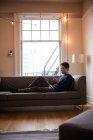 Hombre usando tableta digital y teléfono móvil en la sala de estar en casa - foto de stock