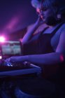 Weiblicher DJ hört Kopfhörer, während er in der Bar Musik abspielt — Stockfoto
