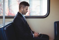 Geschäftsmann hört Musik und nutzt Handy im Zug — Stockfoto