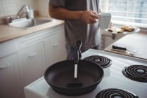 Середній розділ чоловіка зі своєю тарілкою для сніданку та чашкою кави, що стоїть на кухні — стокове фото