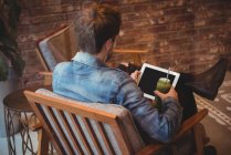 Mann benutzt digitales Tablet, während er im Café Saft trinkt — Stockfoto