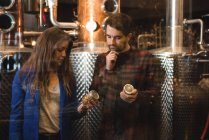 Homme et femme examinant des bouteilles dans une usine de bière — Photo de stock