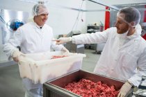 Butchers interacting at meat factory interior — Stock Photo