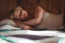 Hermosa mujer durmiendo en la cama en el dormitorio en casa - foto de stock
