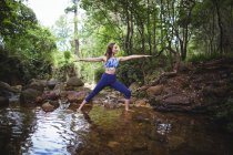 Femme effectuant du yoga en forêt par une journée ensoleillée — Photo de stock