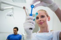 Dentista olhando para ferramentas odontológicas na clínica — Fotografia de Stock