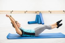 Mulher adulta média realizando exercício de alongamento no ginásio — Fotografia de Stock