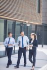 Selbstbewusster Geschäftsmann spaziert mit Kollegen vor Bürogebäude — Stockfoto