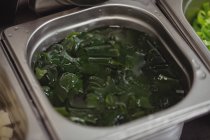 Close-up of chopped leafy vegetables in container in restaurant — Stock Photo