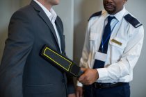 Oficial de segurança do aeroporto usando um detector de metais de mão para verificar um viajante no aeroporto — Fotografia de Stock