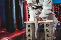 Karate player breaking wooden plank in fitness studio — Stock Photo