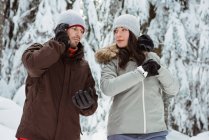 Чоловік розмовляє на мобільному телефоні і жінка перевіряє час на снігу покритій горі — стокове фото