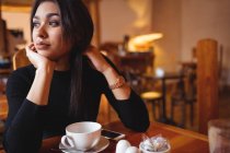 Продумана жінка сидить у кав'ярні — стокове фото