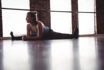 Young female dancer performing stretching exercise in dance studio — Stock Photo
