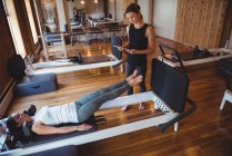 Trainer assisting woman with digital tablet while practicing pilates in fitness studio — Stock Photo