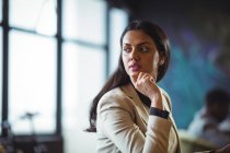Задумчивая деловая женщина смотрит в сторону в офисе — стоковое фото