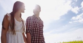 Paar an einem sonnigen Tag Händchen haltend auf dem Feld — Stockfoto