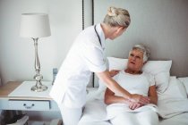 Женщина-врач взаимодействует со старшим пациентом дома — стоковое фото