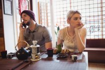 Hombre ignorando a la mujer mientras habla por teléfono en el restaurante - foto de stock