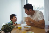 Батько і син, взаємодіючих в будинку маючи сніданок — стокове фото