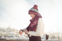 Усміхнена жінка в зимовому одязі перевіряє свій смарт-годинник — стокове фото