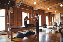 Entrenador ayudando a la mujer a practicar pilates en el gimnasio - foto de stock
