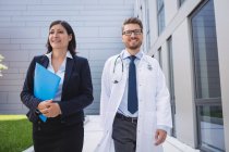 Lächelnde Ärzte beim gemeinsamen Spaziergang in Krankenhausräumen — Stockfoto