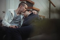 Гей пара цілується і обіймається на дивані вдома — стокове фото