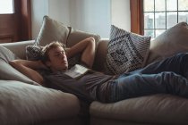 Мужчина спит на диване с книгой на груди в гостиной — стоковое фото