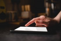 Женская рука с помощью цифрового планшета на кухне дома — стоковое фото