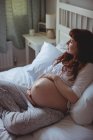 Продумана вагітна жінка розслабляється на ліжку в спальні — стокове фото