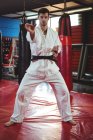Retrato del jugador de karate realizando postura de karate en el gimnasio - foto de stock