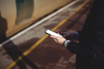 Обрезанный взгляд на бизнесмена с помощью мобильного телефона на вокзале — стоковое фото