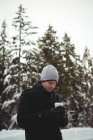 Uomo in abbigliamento caldo in possesso di tazza di caffè durante l'inverno — Foto stock