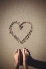 Низкая часть женщины, стоящей рядом с сердцем, нарисованной на пляже — стоковое фото
