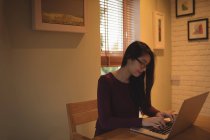Frau benutzt Laptop auf Tisch im heimischen Wohnzimmer — Stockfoto