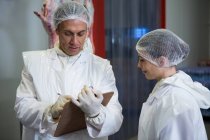 Due macellai discutono il rapporto di documentazione alla fabbrica di carne — Foto stock