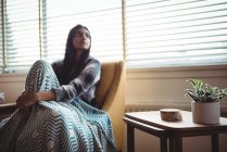 Nachdenkliche Frau sitzt auf Sofa-Stuhl im heimischen Wohnzimmer — Stockfoto