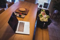 Ordenador portátil en mesa de madera con bebé en el fondo en casa - foto de stock