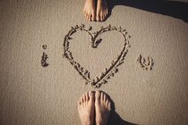 Feet of couple standing near I love you drawn on the beach — Stock Photo